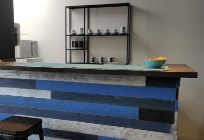 Communal kitchen area with a blue wood-paneled bar and modern pendant lighting.