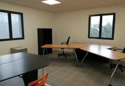 Spacious private office with several wooden desks and large windows.
