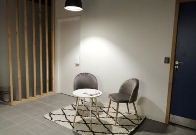 Small waiting area with two grey velvet chairs and a round coffee table.