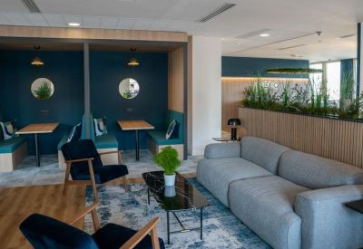 Cozy breakout area with a gray sofa, blue armchairs, and private seating booths.