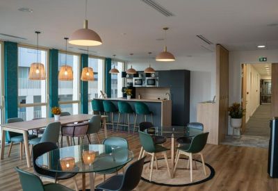 Spacious communal lounge with modern dining tables, bar seating, and colorful pendant lights.