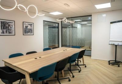 Large meeting room with a light wood table, colourful chairs, and unique halo pendant lights.