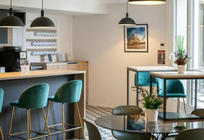 Stylish breakroom with teal bar stools, a breakfast counter, and modern black pendant lighting.