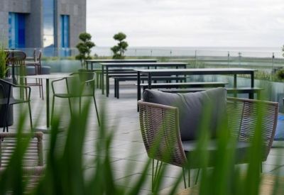 Outdoor rooftop terrace featuring modern seating, greenery, and a view of the airport control tower.