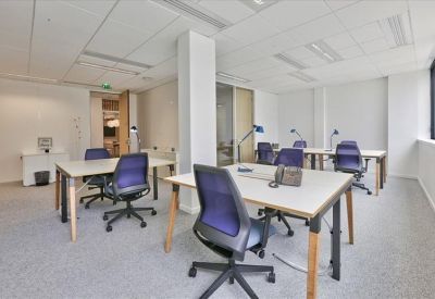 Bright open-plan office space with white desks, purple ergonomic chairs, and large windows.