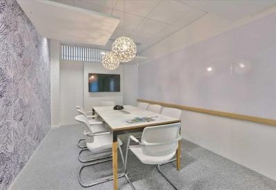 Modern meeting room featuring a white marble table, spherical wire pendant lights, and a decorative leaf-patterned wall.