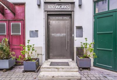 Exterior entrance of 1010.WORKS coworking space featuring a metal door and potted plants.