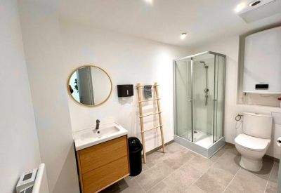 Modern bathroom with a glass shower cubicle, wooden vanity, and white tiled walls.