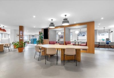 Spacious communal lounge and coworking area with modern furniture and warm wood accents.