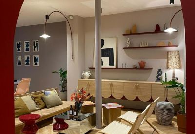 Sunlit lounge area with an arched entrance, herringbone wood floors, and modern eclectic furniture.