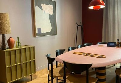 Sophisticated meeting room with a pink oval table, black chairs, and contemporary art.