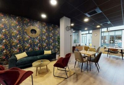 Colorful communal lounge with a floral feature wall, velvet sofa, and dining tables.