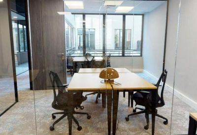 Bright glass-walled private office with two desks and ergonomic chairs.