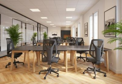 Long open office space with rows of desks and glass partitions.