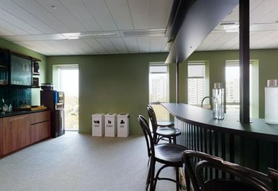 Communal kitchen area with wooden cabinetry and a breakfast bar stool seating area.