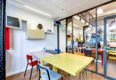 Open-plan office space featuring colorful desks and glass partitions.
