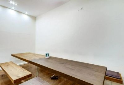 Minimalist dining area with a long wooden table and bench seating.
