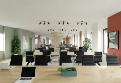 Open-plan office workspace featuring rows of black ergonomic chairs and long light-wood desks.