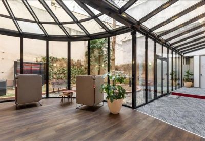 Luminous sunroom lounge with floor-to-ceiling glass walls overlooking a courtyard.