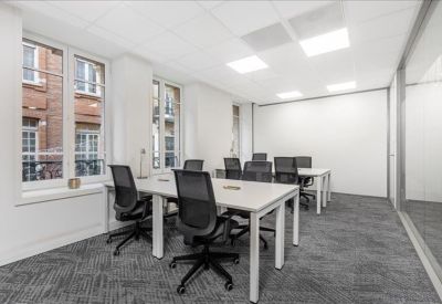 Bright four-person office suite with white desks and views of traditional architecture.