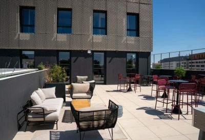 Outdoor terrace with lounge seating and high-top red tables.