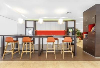 Communal break area with high stools and a vibrant red backsplash.