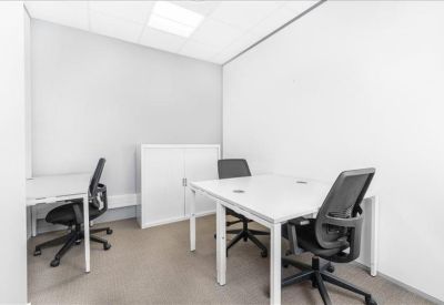 Compact private office with three black ergonomic chairs and white desks.