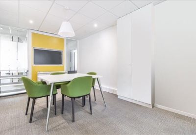 Small breakout room featuring green chairs and a yellow accent wall with a monitor.