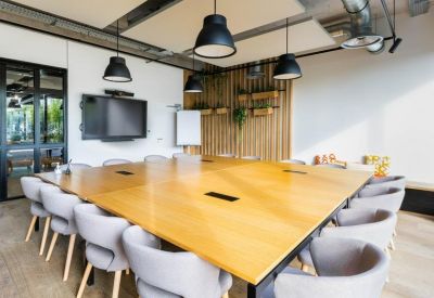 Large wooden conference table in a modern meeting room with industrial lighting and wood slat walls.