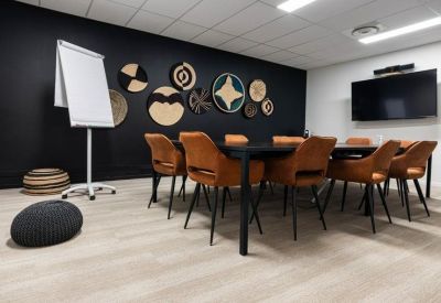 Meeting room featuring leather chairs, a black feature wall with circular decor, and a wall-mounted screen.