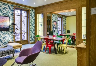 Bright meeting room with tropical leaf wallpaper and colorful chairs around a large table.