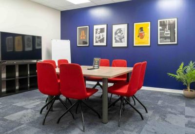 Meeting room with a bold blue accent wall, red chairs, and framed artwork.
