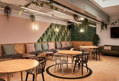 Bright lounge featuring a long bench with pastel cushions and a tropical leaf accent wall.