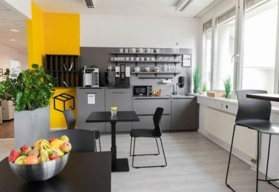 Modern communal kitchen and dining area featuring a bright yellow accent wall.