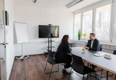 Professional meeting room with a large screen, whiteboard, and hardwood flooring.
