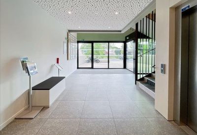 Lobby area featuring large glass doors, a modern bench, and an elevator bank.