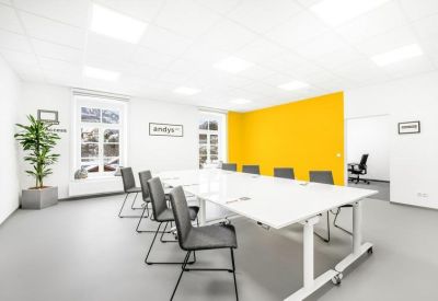 Meeting room with a large white table, grey seating, and a vibrant yellow feature wall.