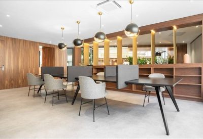 Modern coworking area with grey armchairs, wooden partitions, and spherical pendant lights.