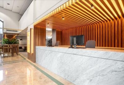 Reception desk with a white marble finish and a warm wooden slat ceiling feature.