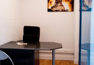 Private office space with a dark desk, ergonomic chair, and Eiffel Tower wall art.