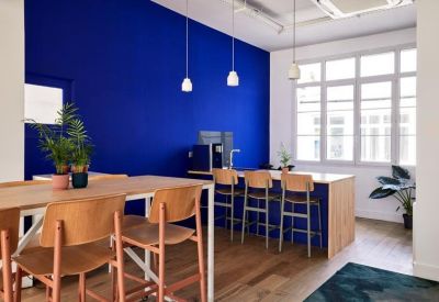 Communal kitchen and dining area with a bold blue feature wall and wooden bar stools.