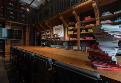 Long library-style table surrounded by floor-to-ceiling bookshelves and a large screen.