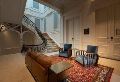 Spacious lobby featuring a leather sofa, red patterned rug, and grand staircase.