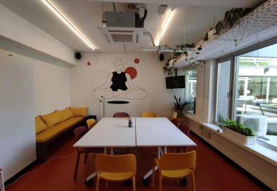 Meeting room with a white table, yellow chairs, and a wall mural featuring red circles.