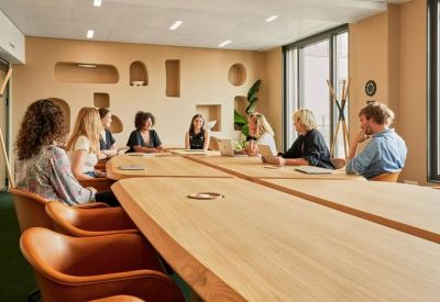 Modern meeting room with a large wooden table, leather chairs, and recessed wall niches.