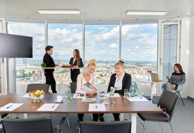 Spacious boardroom with a large wooden table and floor-to-ceiling windows overlooking the skyline.