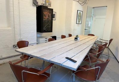 Large meeting room featuring a long wooden board table and leather chairs.