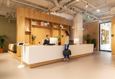 Sleek white reception desk with wood-paneled walls and a digital kiosk.