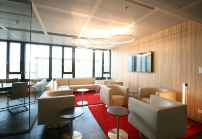 Vibrant communal lounge featuring cream armchairs and striking red area rugs.
