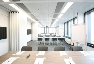 Bright conference room with a long table, ergonomic chairs, and a mobile whiteboard.
